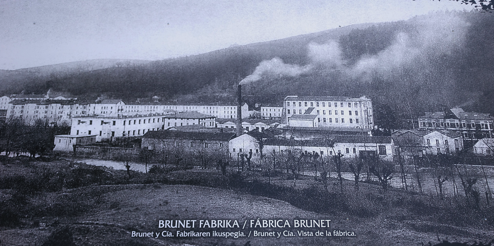 Panorama de la fábrica Brunet desde la otra orilla del río, con chimenea, naves y palacete