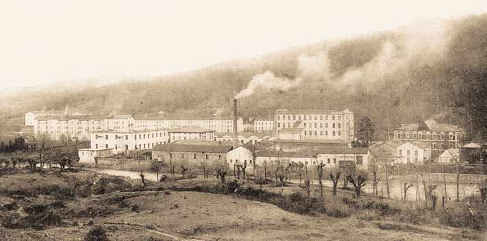 Panorama de la fábrica y su barrio con humo en la chimenea